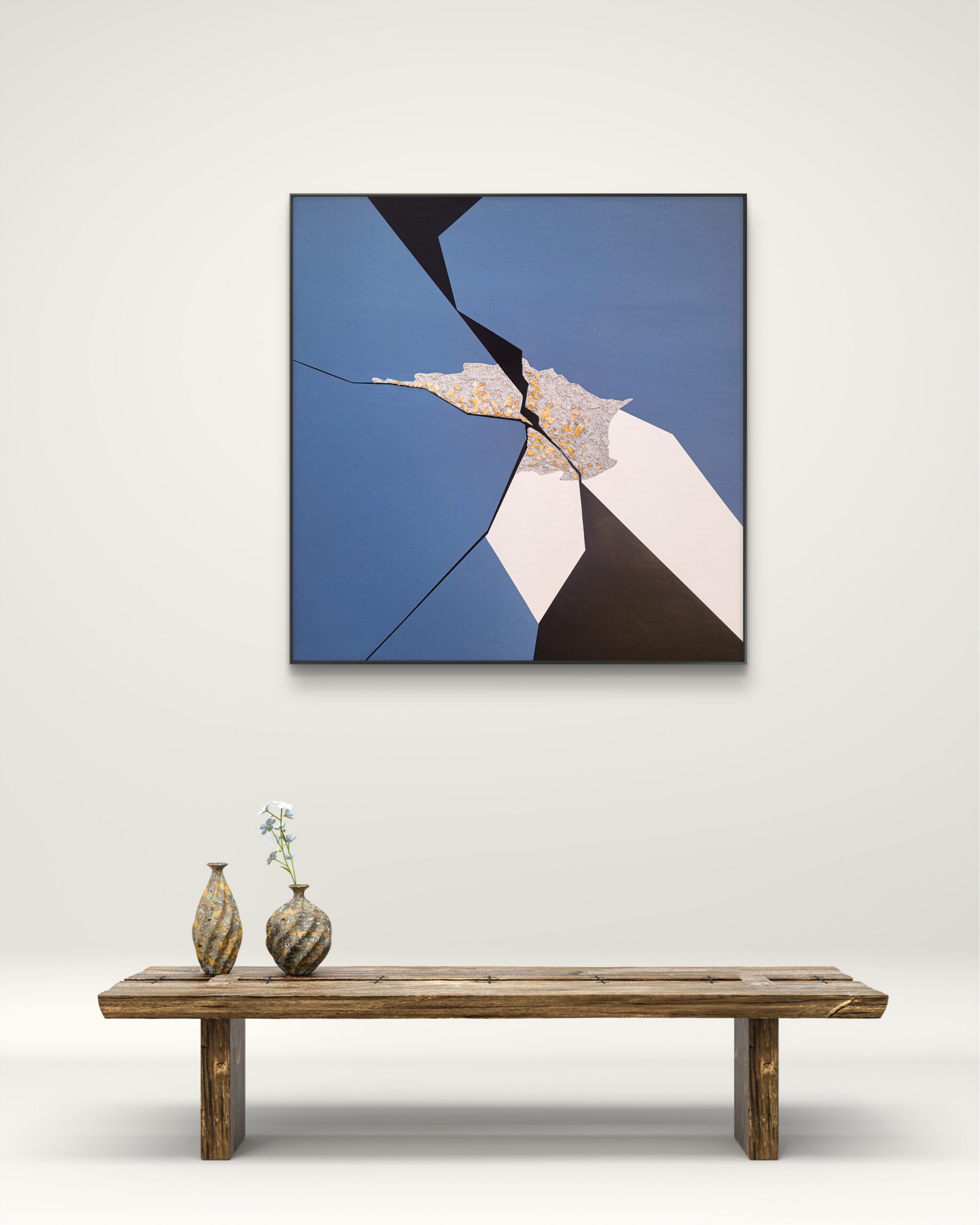 Minimalist abstract art with blue, black, and white geometric shapes and a central gold-textured crack by Veronika Obushikhina, displayed above a rustic wooden bench